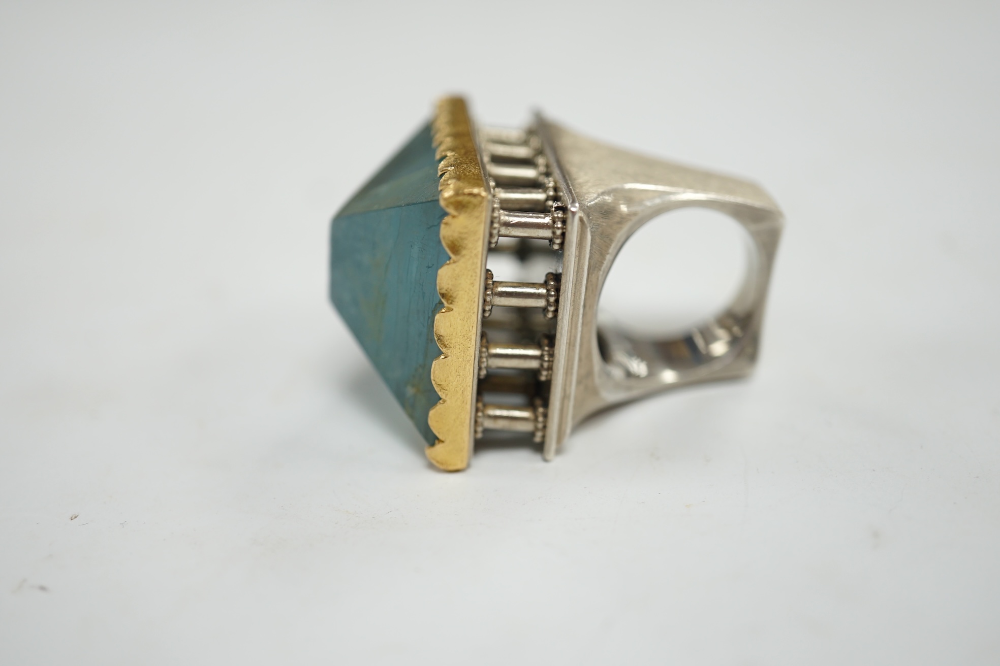 An unusual recent German 925, yellow metal and shaped cut aquamarine set architectural dress ring, the stone weighing approximately 79.00ct, size O/P, gross weight 67 grams. Condition - fair to good